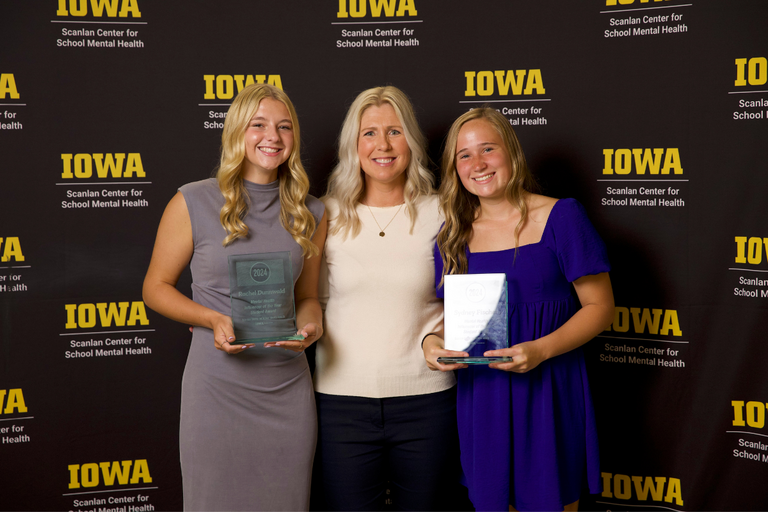 Three people standing holding their awards smiling. 