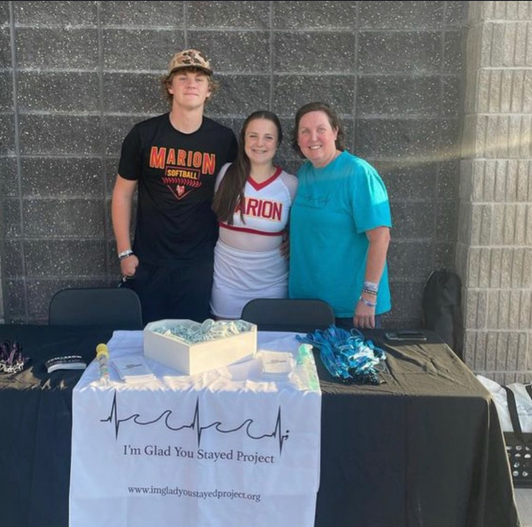 Three people standing behind a table looking into the camera smiling. 