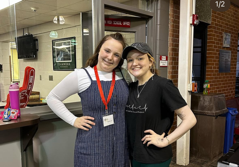 Two people looking into the camera with their hands on their hips smiling.