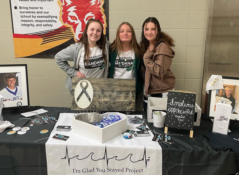 Three people standing behind a table looking into the camera smiling. 