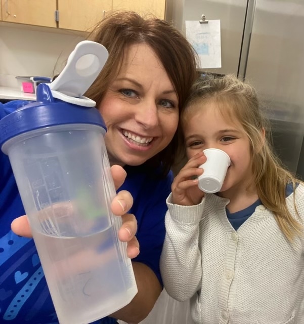 Two people smiling at the camera holding up a water bottle