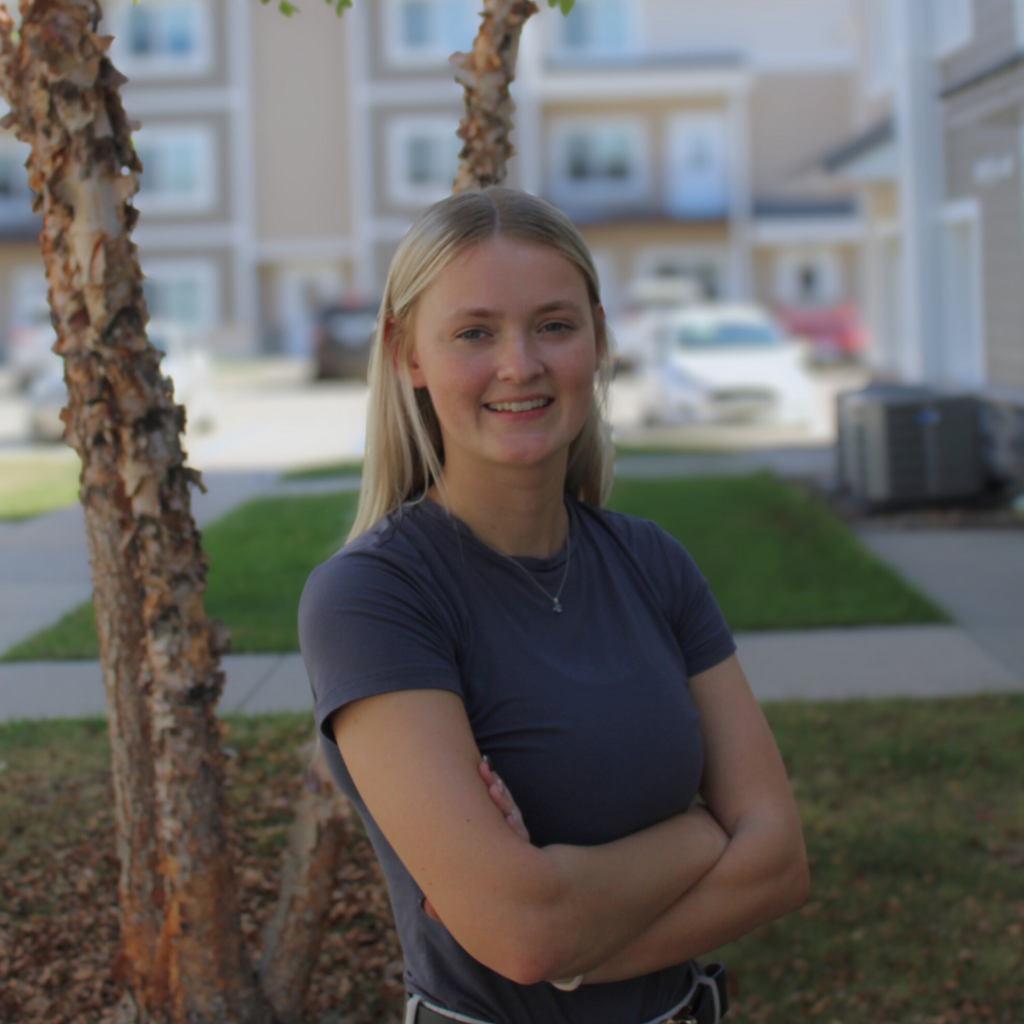 Girl standing with her arms crossed outside.