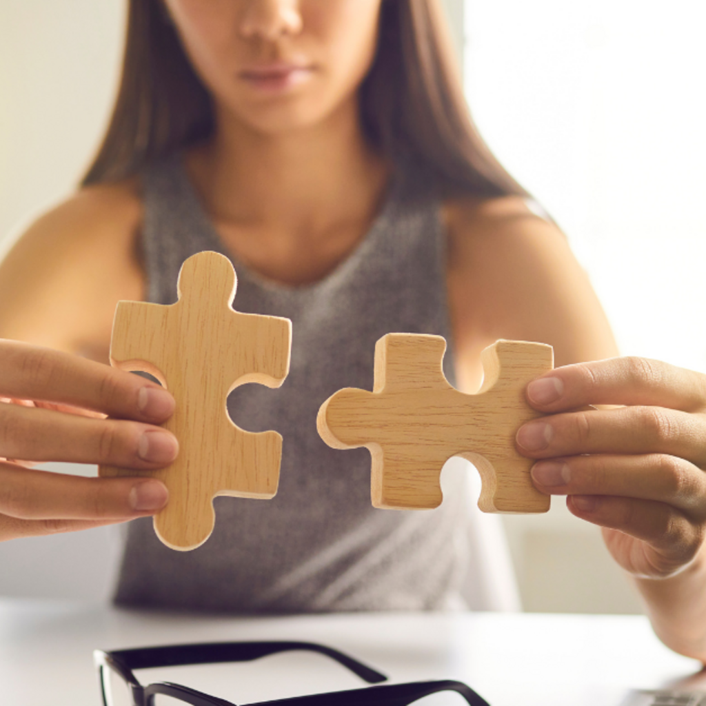 Woman sitting at desk fitting two puzzle pieces together