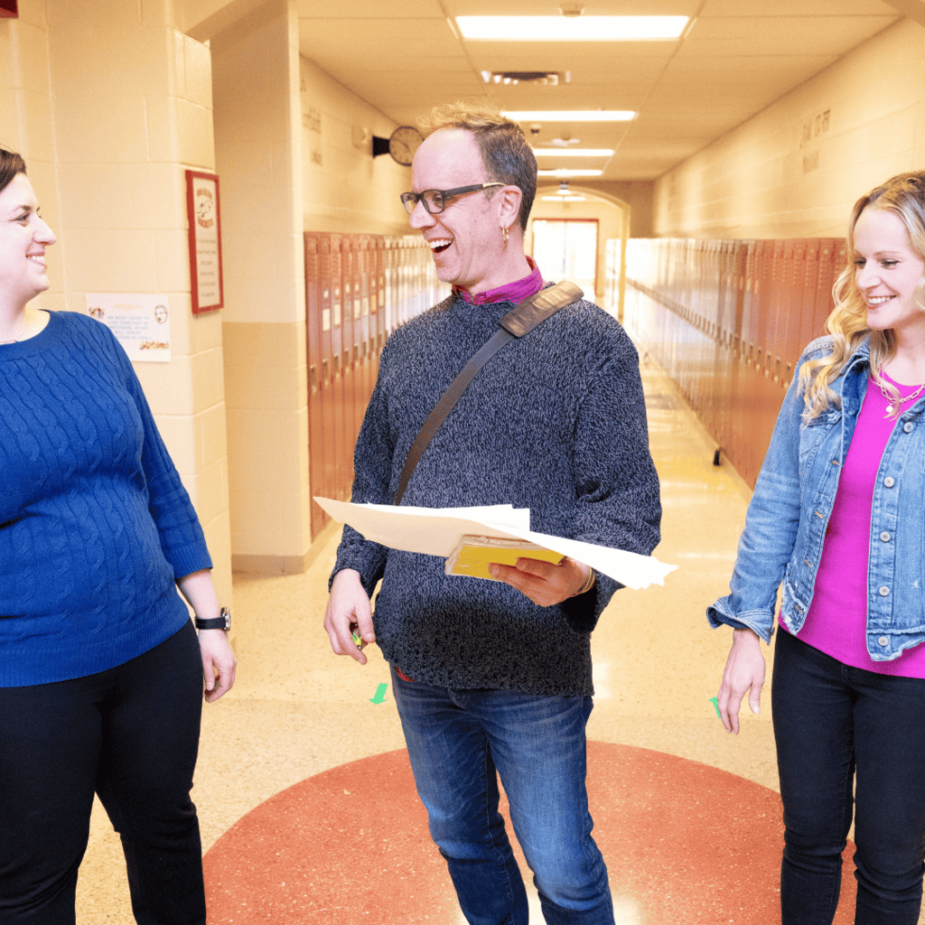 Three educators talking in a school hallway