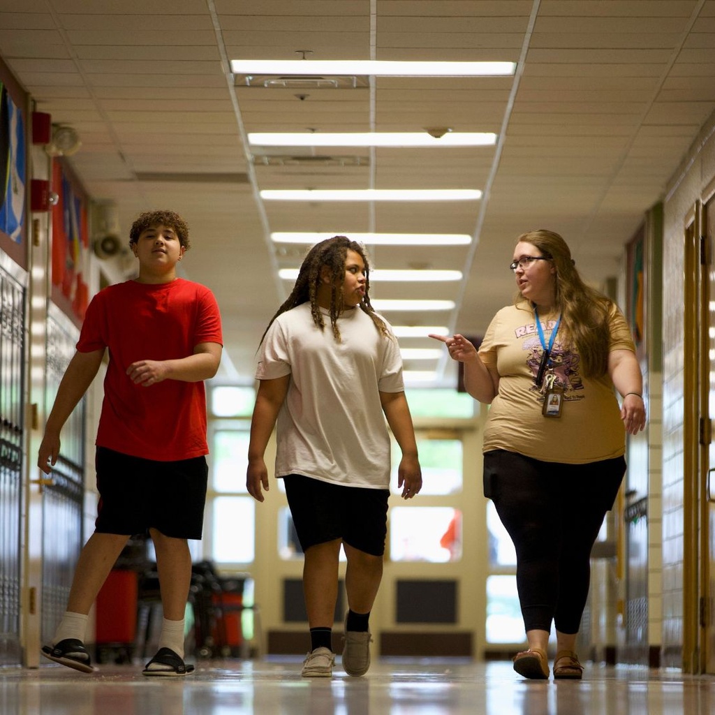 A teacher walking down the hallway with two students