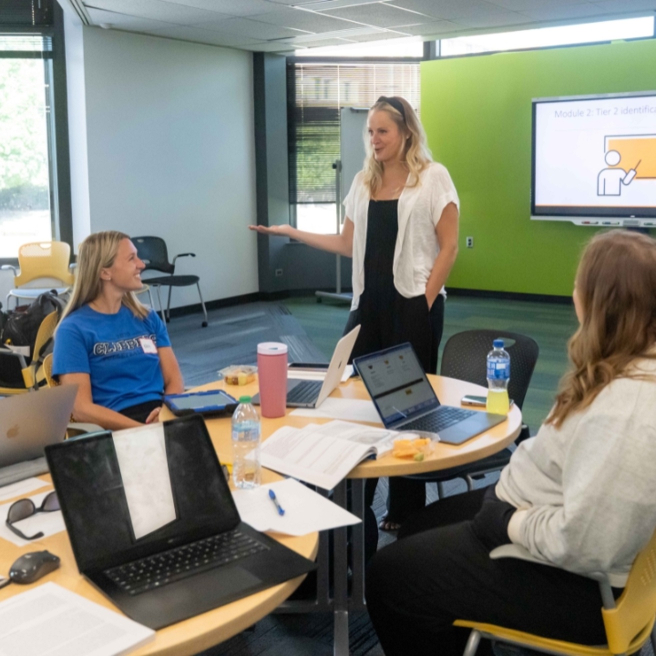 Dr. Allison Bruhn leading a training; talking with a table of educators