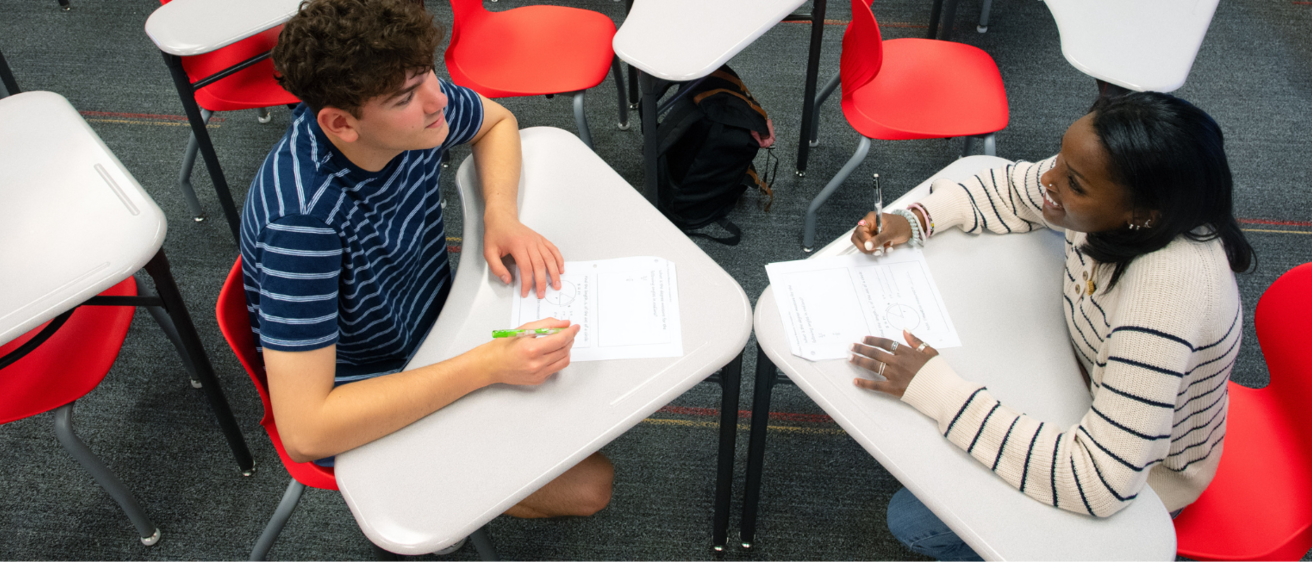 Two students sitting at desks facing each other