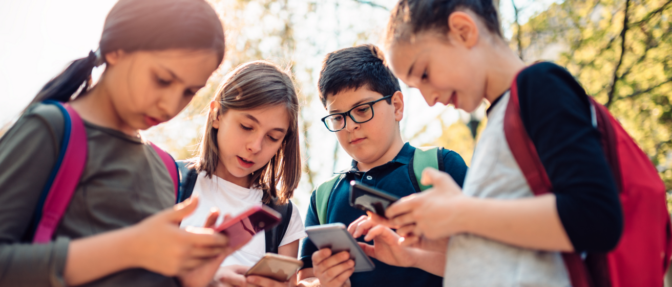 Photo of four young students using cell phones