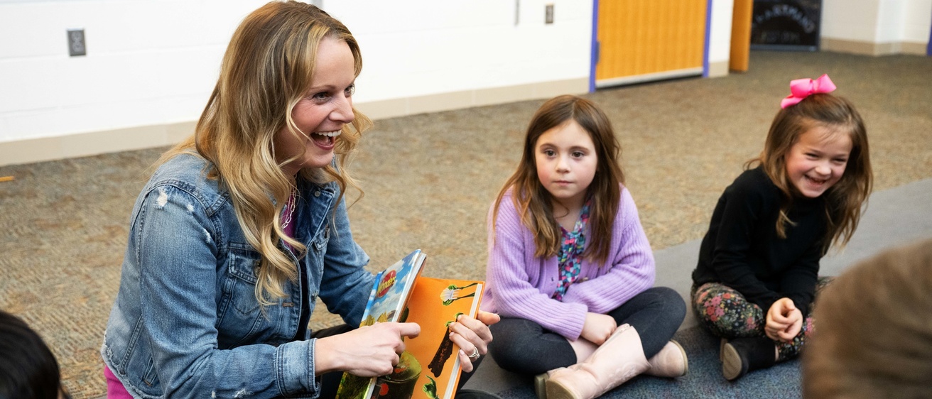 woman reading book to group of young kids
