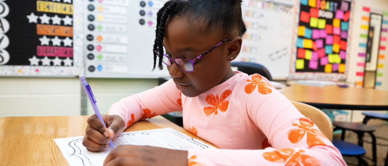 Girl writing at school desk