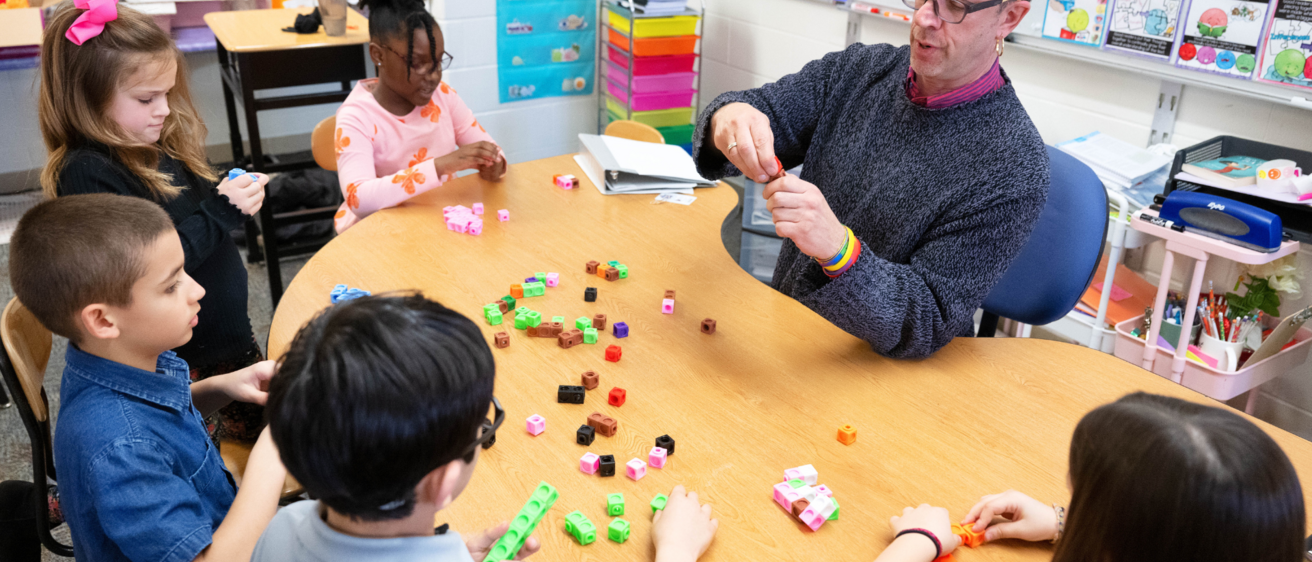 Teacher working at table with four students