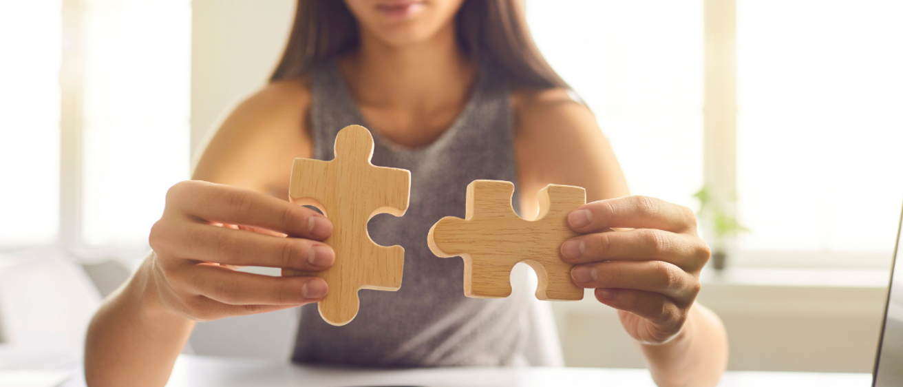 Woman sitting at desk fitting two puzzle pieces together