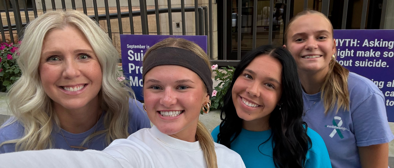 four people smiling at a camera 