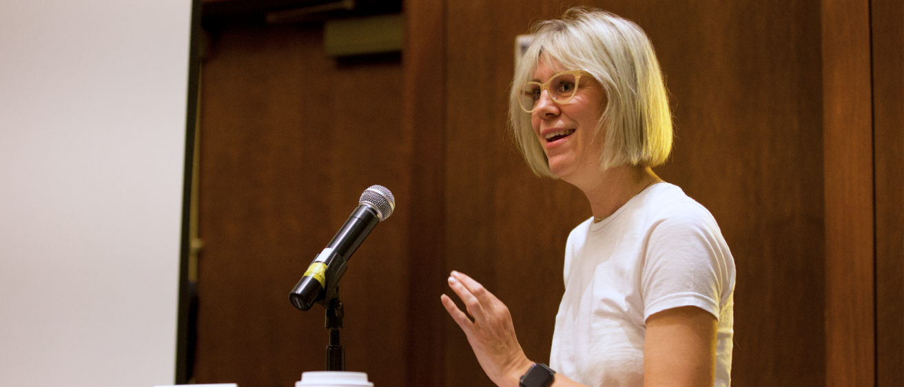 A person speaking into a microphone and smiling 