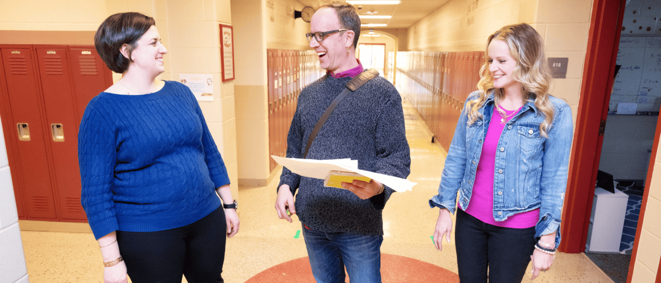 Three educators talking in a school hallway