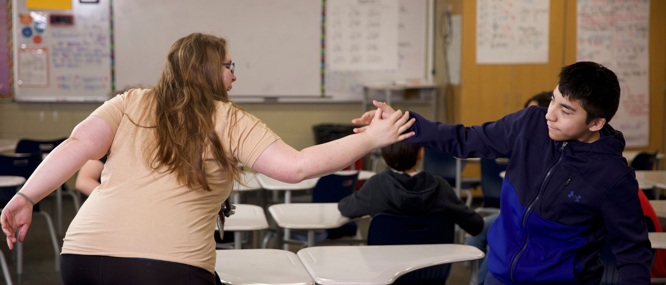 Teacher high fiving a student in a classroom