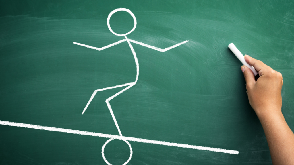 Person drawing a stick figure balancing on a chalkboard