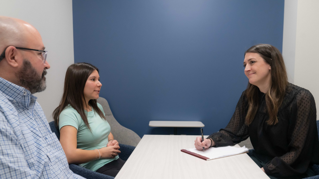 A counselor talking with a parent and teen at a table