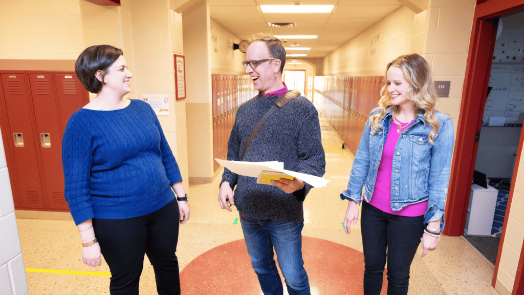 Three educators talking in a school hallway
