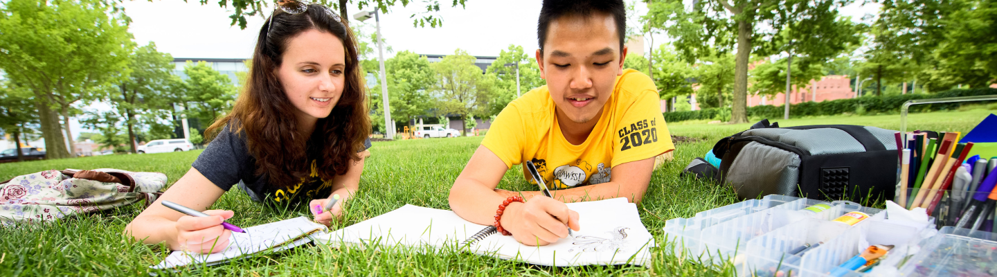 Two college students studying in grass