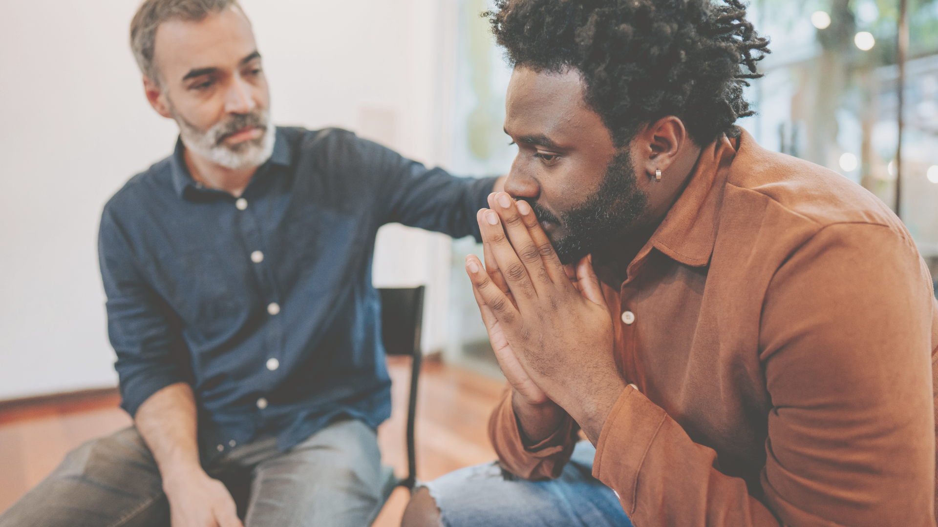 Man placing comforting hand on other man's shoulder